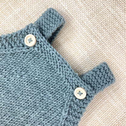 close up photo of the yoke and straps of a baby romper knitting pattern