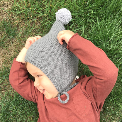 a toddler pixie hat pattern. photo shows toddler laying on grass wearing a pixie hat