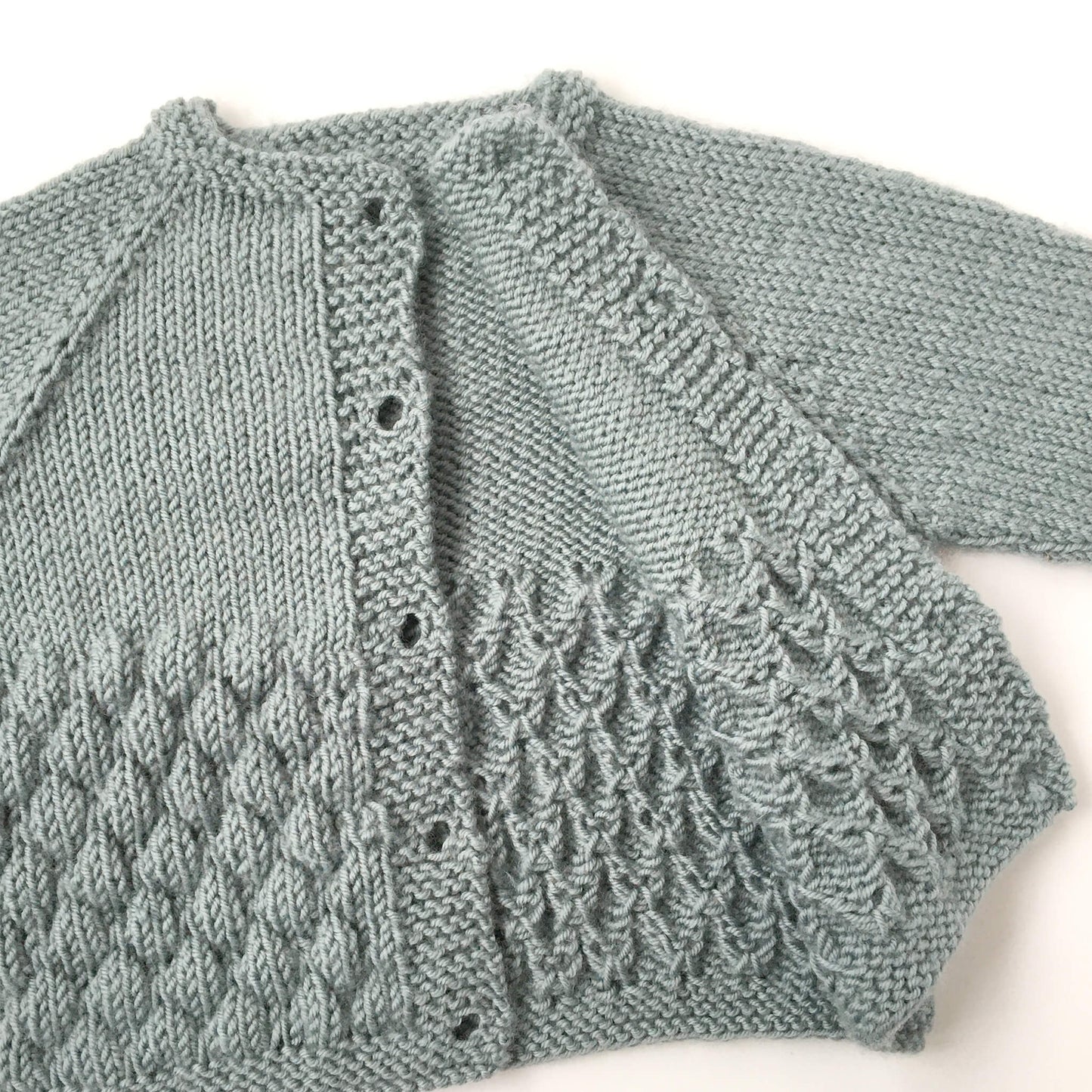 a top down knitting pattern for a baby cardigan. The cardigan is open to show the pattern on the inside