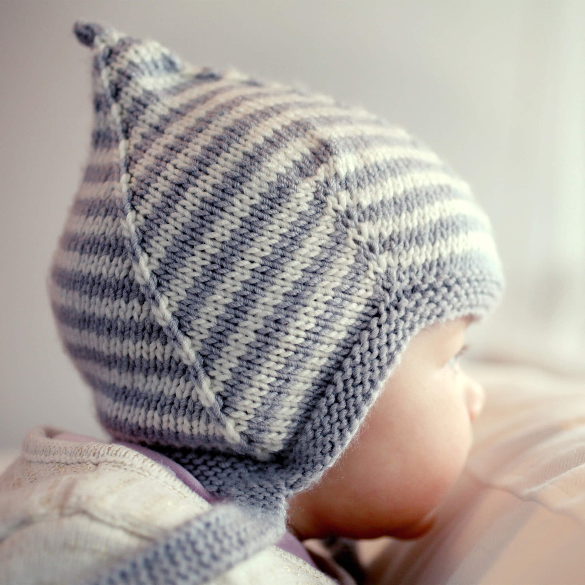 a vintage style pixie hat knitting pattern with grey and white stripes